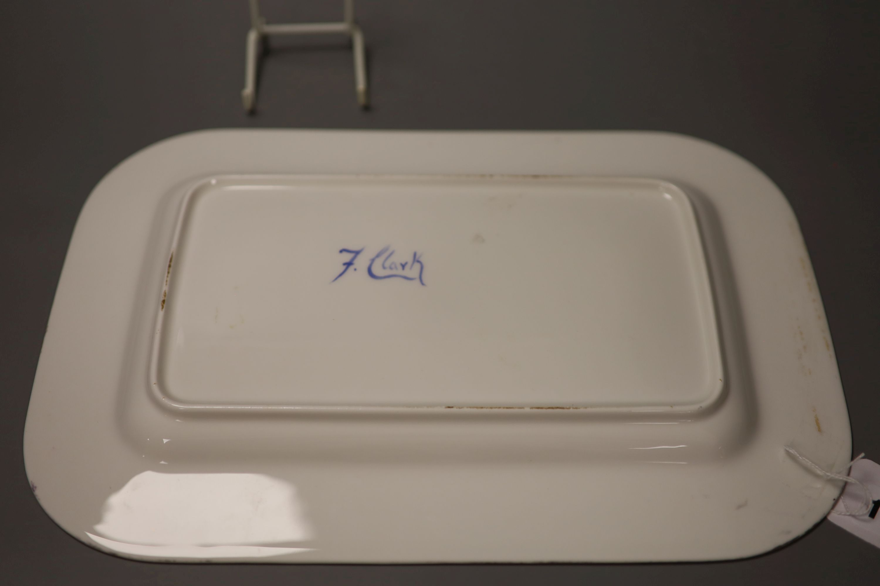 A rectangular dish with rounded corners painted with painted with sheep, a man and dog and a country house by Francis Clark, signed fro